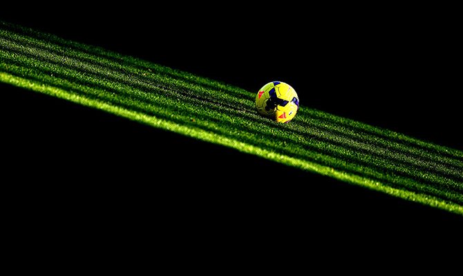 Balón amarillo iluminado sobre el césped en la oscuridad. Cuotas para el Olimpia vs Internacional.