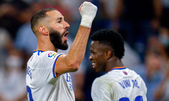 Karim Benzema celebrando con el puño en alto, con Vinícius de fondo. Apuestas Inter vs Real Madrid.