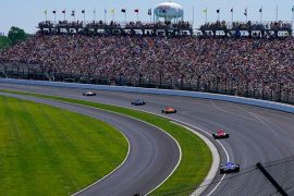 Varios vehículos pasan una curva en las 500 Millas de Indianapolis 2022